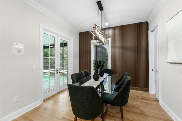dining area with a notable chandelier, crown molding, french doors, light wood-style flooring, and baseboards