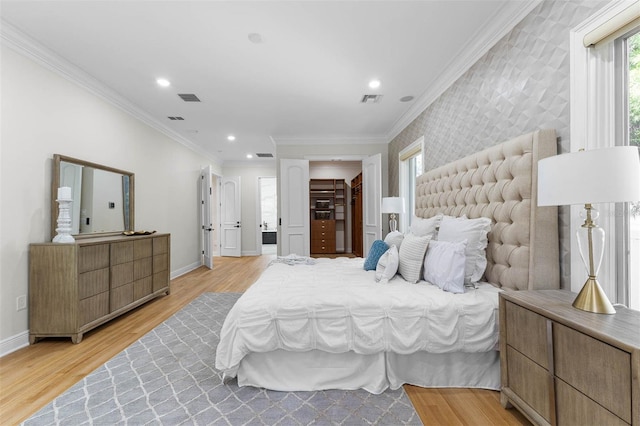 bedroom with baseboards, crown molding, and light wood finished floors