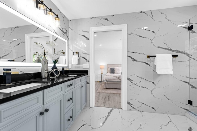 bathroom featuring stone wall, marble finish floor, a sink, double vanity, and ensuite bathroom