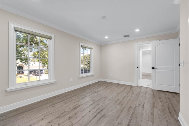 spare room featuring light wood finished floors, baseboards, visible vents, and ornamental molding