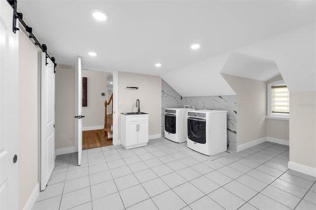laundry area with baseboards, a barn door, washing machine and dryer, a sink, and cabinet space