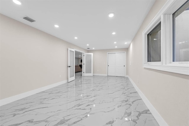 spare room with marble finish floor, baseboards, visible vents, and recessed lighting