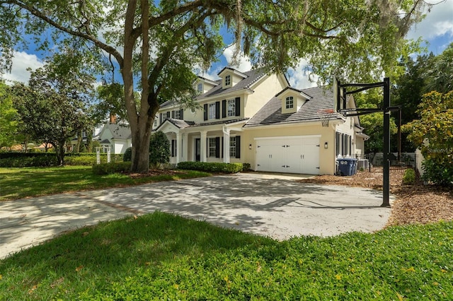 view of front of home featuring driveway, a tiled roof, a garage, a front lawn, and stucco siding