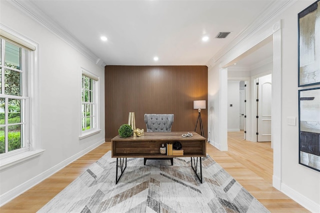 office space featuring light wood finished floors, visible vents, ornamental molding, and an accent wall