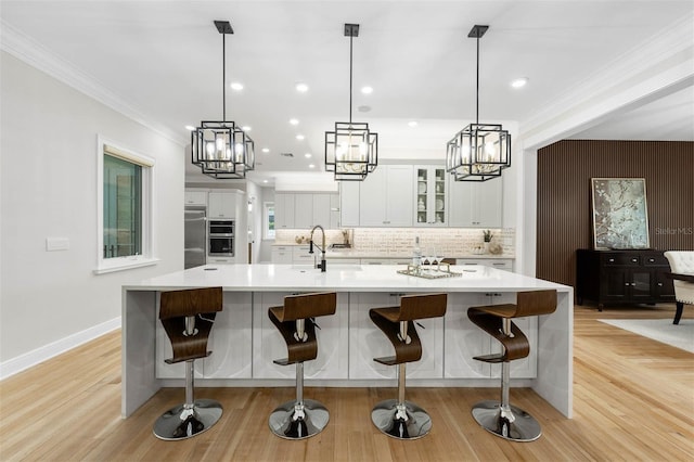 kitchen with white cabinetry, light countertops, crown molding, stainless steel appliances, and backsplash