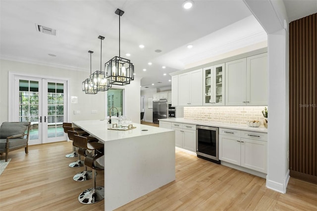 kitchen with visible vents, ornamental molding, beverage cooler, built in fridge, and french doors