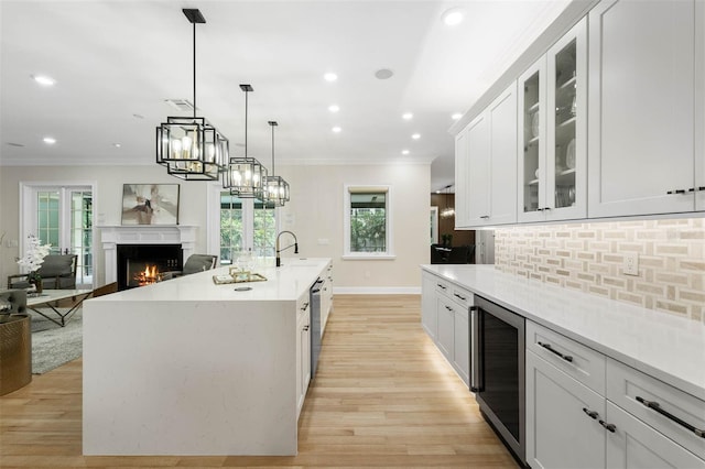 kitchen featuring a warm lit fireplace, beverage cooler, backsplash, and ornamental molding
