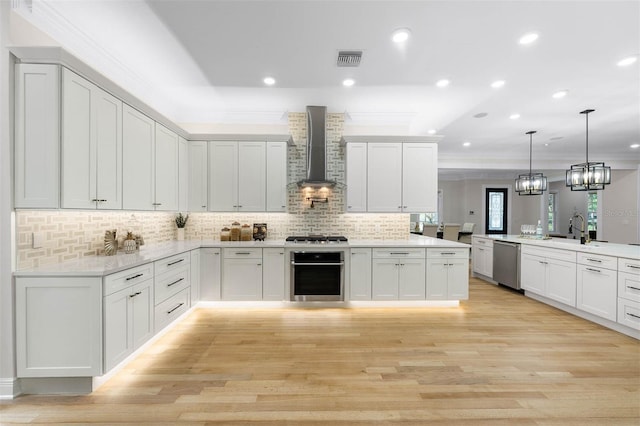 kitchen with visible vents, wall chimney range hood, stainless steel appliances, and crown molding