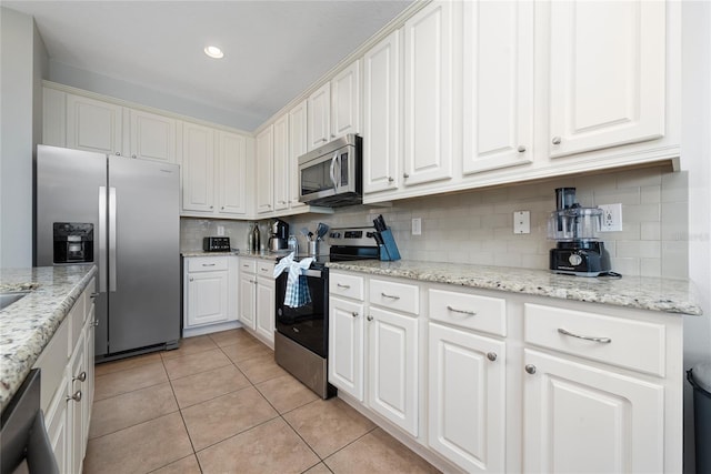 kitchen featuring decorative backsplash, appliances with stainless steel finishes, light stone countertops, white cabinetry, and light tile patterned flooring