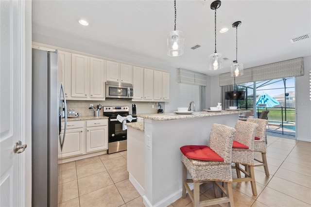 kitchen with a breakfast bar, a center island, hanging light fixtures, white cabinetry, and stainless steel appliances