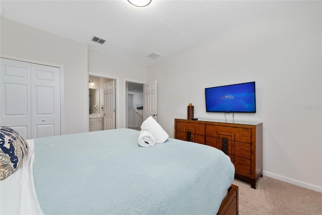 carpeted bedroom with ensuite bath and a closet