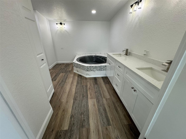 bathroom featuring vanity, a bath, hardwood / wood-style flooring, and a textured ceiling