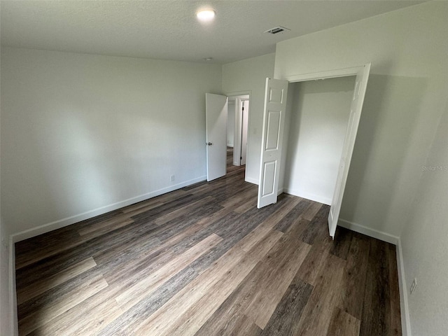 unfurnished bedroom with dark wood-type flooring and a closet