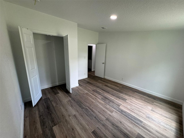 unfurnished bedroom featuring dark hardwood / wood-style floors, a closet, and a textured ceiling