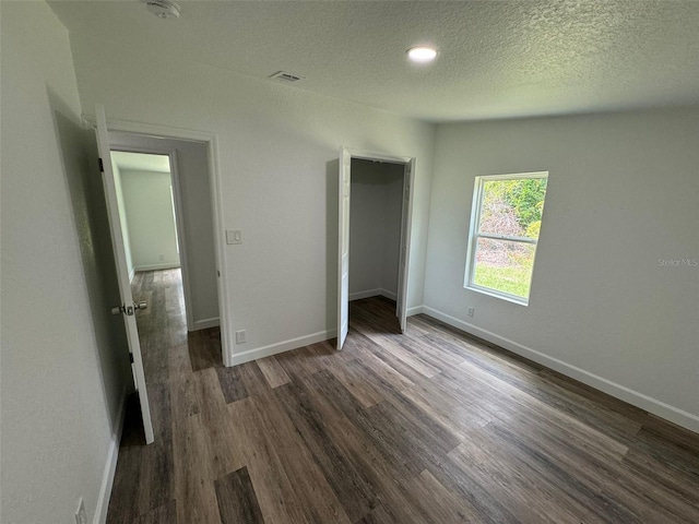 unfurnished bedroom with a closet, dark hardwood / wood-style floors, and a textured ceiling