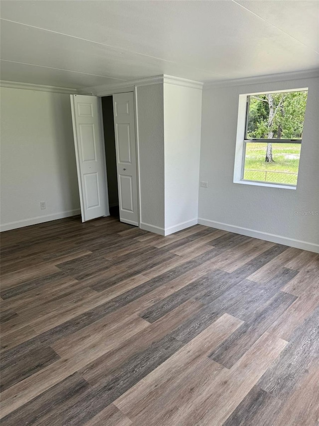 unfurnished bedroom featuring dark wood-type flooring and crown molding