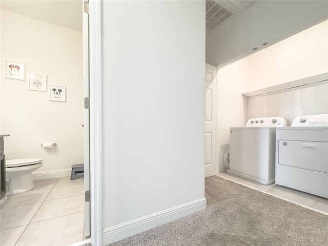 laundry area with washer and clothes dryer and light tile patterned flooring