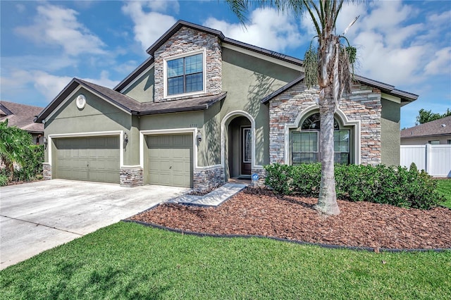 traditional-style house featuring concrete driveway, fence, stone siding, and stucco siding