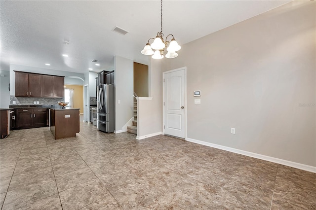 kitchen featuring stainless steel refrigerator, dark brown cabinetry, a center island, an inviting chandelier, and pendant lighting