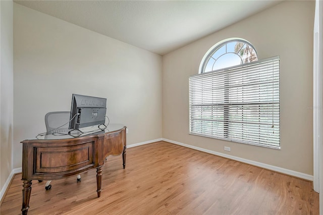 home office with a healthy amount of sunlight, vaulted ceiling, and light hardwood / wood-style flooring