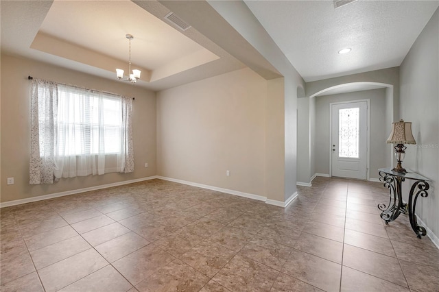 entryway featuring a tray ceiling, light tile patterned floors, a healthy amount of sunlight, and an inviting chandelier