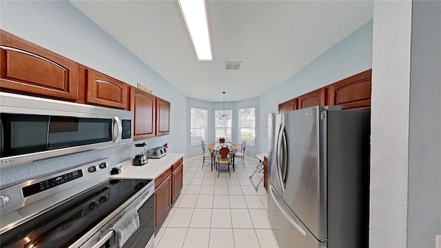 kitchen with light tile patterned floors, hanging light fixtures, and appliances with stainless steel finishes