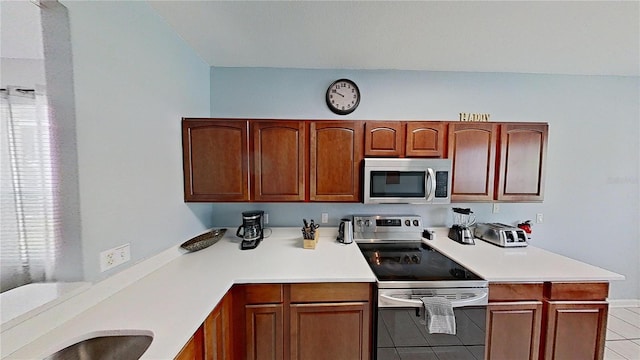 kitchen with a wealth of natural light, light tile patterned floors, sink, and appliances with stainless steel finishes