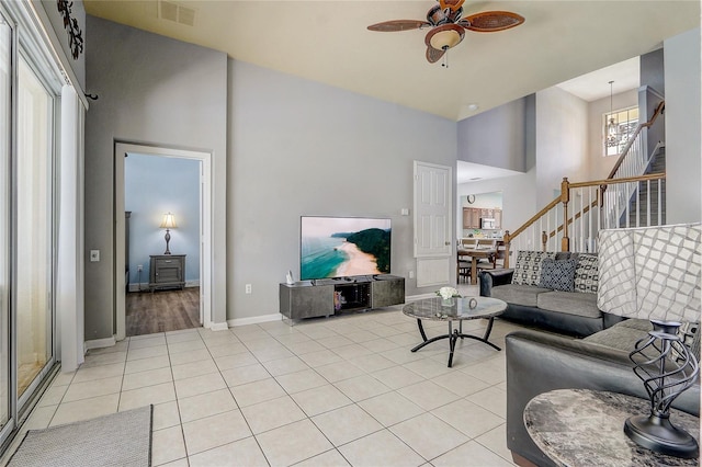 tiled living room featuring a high ceiling and ceiling fan with notable chandelier