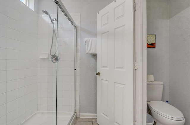 bathroom with tile patterned floors, toilet, and an enclosed shower