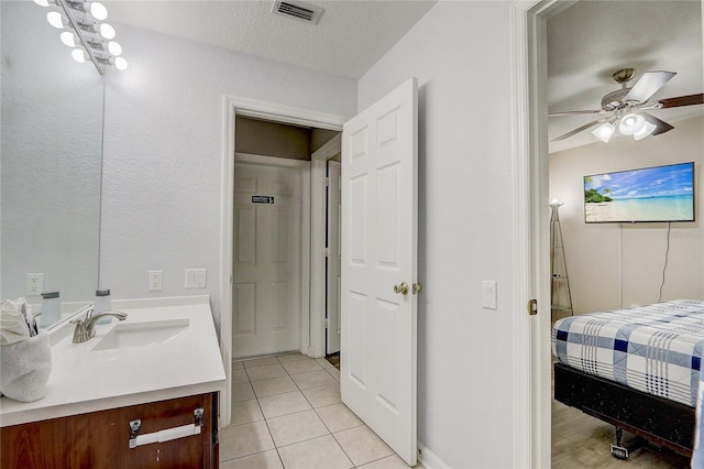 bathroom with ceiling fan, tile patterned flooring, vanity, and a textured ceiling