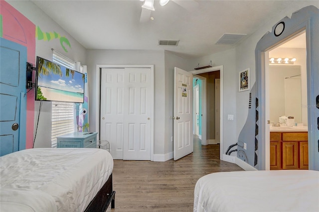 bedroom featuring ceiling fan, sink, wood-type flooring, connected bathroom, and a closet