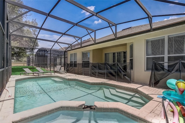 view of swimming pool featuring glass enclosure, a patio area, and an in ground hot tub