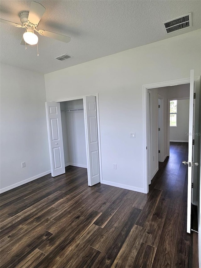 unfurnished bedroom featuring a textured ceiling, ceiling fan, a closet, and dark hardwood / wood-style floors