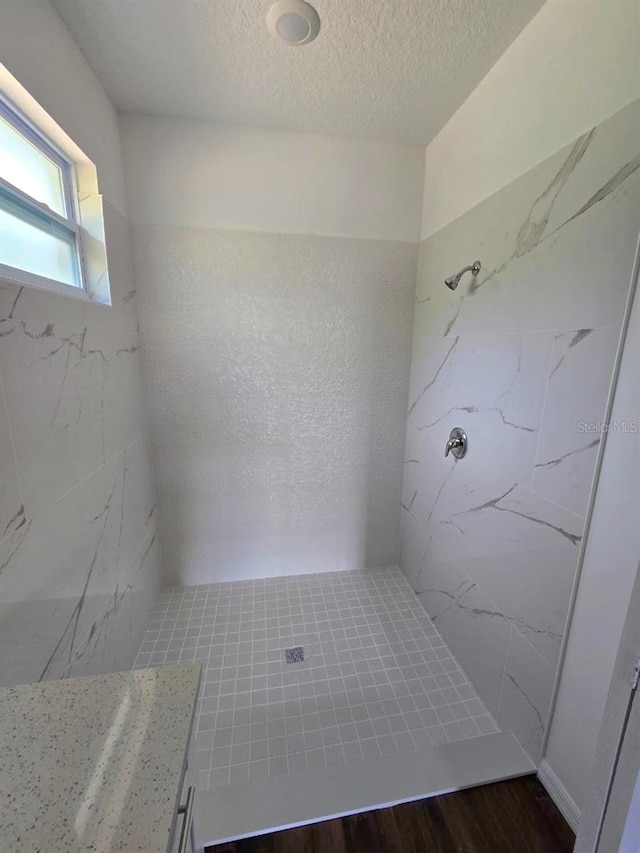 bathroom with tiled shower, hardwood / wood-style floors, and a textured ceiling