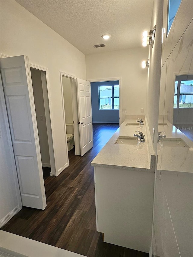 bathroom featuring hardwood / wood-style floors, vanity, a textured ceiling, and toilet