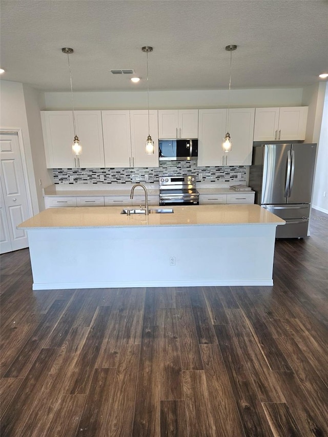 kitchen featuring white cabinets, decorative light fixtures, and stainless steel appliances