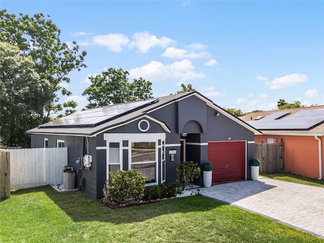 ranch-style house with a garage, a front yard, and solar panels