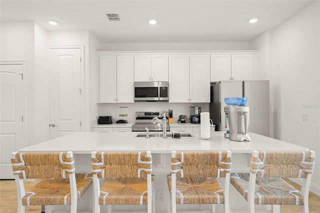 kitchen featuring a breakfast bar, stainless steel appliances, and a kitchen island with sink