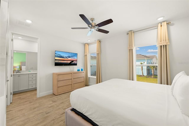 bedroom featuring sink, light hardwood / wood-style flooring, ensuite bath, and ceiling fan