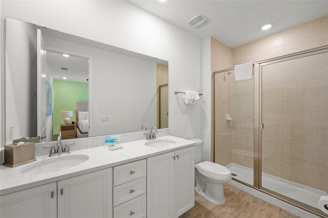 bathroom featuring a shower with door, vanity, and toilet