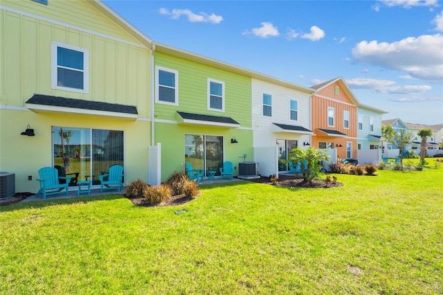 rear view of property with a lawn and central air condition unit