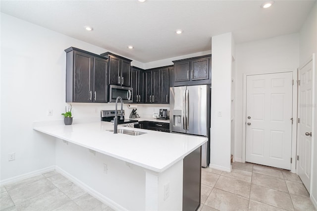 kitchen with light tile patterned flooring, sink, kitchen peninsula, and stainless steel appliances