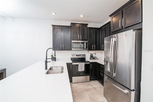 kitchen featuring a textured ceiling, light tile patterned floors, sink, and appliances with stainless steel finishes