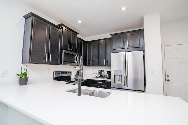 kitchen with kitchen peninsula, a textured ceiling, and stainless steel appliances