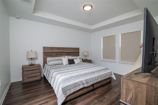 bedroom featuring a textured ceiling, a raised ceiling, and dark hardwood / wood-style floors