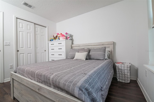 bedroom featuring a textured ceiling, dark wood-type flooring, and a closet