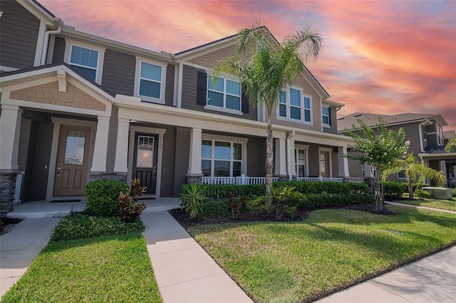2135 Valencia Blossom St, Clermont, FL 34711 - view of front of house featuring a porch, a front yard, and stone siding