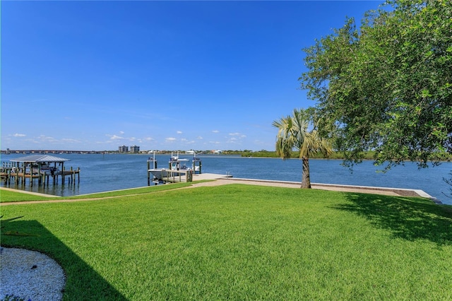 view of dock with a lawn and a water view