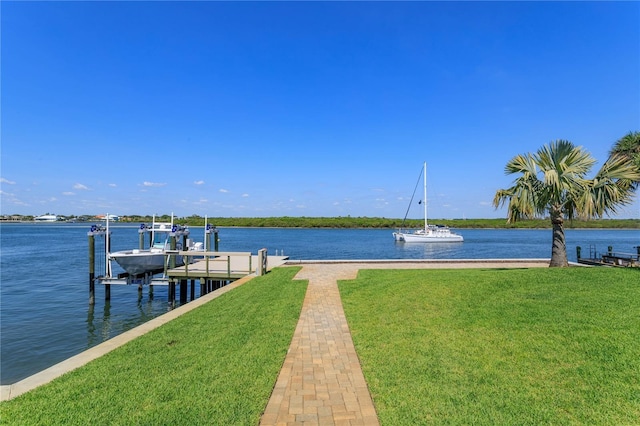 dock with boat lift, a water view, and a yard