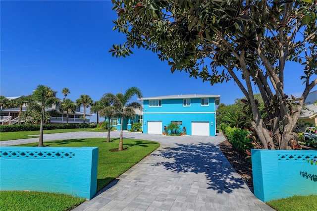 view of front of house featuring an attached garage, decorative driveway, and a front yard